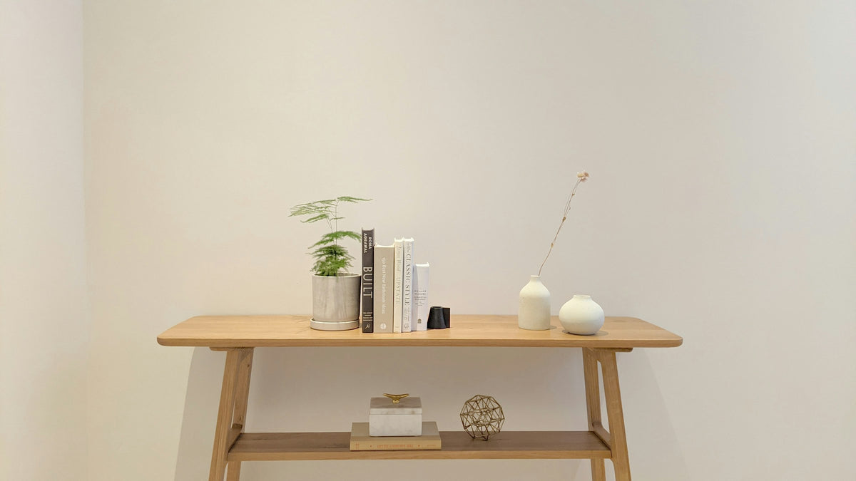 Wooden console table styled with books, a potted plant and ceramic vases